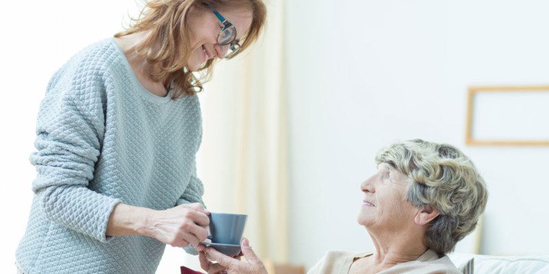 Jüngere Frau reicht einer älteren Dame eine Tasse Tee